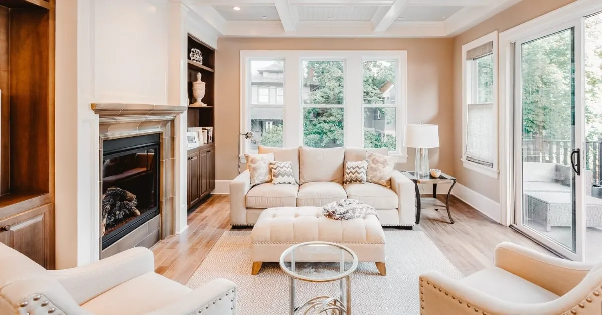 A beautifully designed living room with large windows, a cozy fireplace, and elegant furnishings, creating a warm and inviting atmosphere.