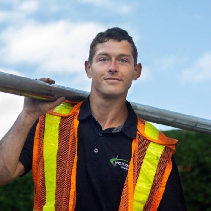 Screw piles installer with an helical pile on his back